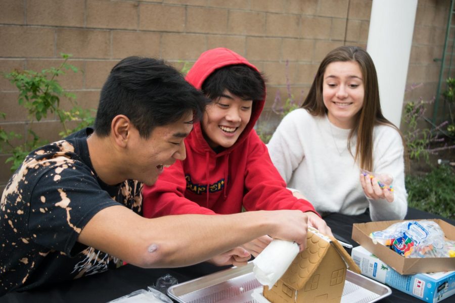 OH SNAP!: Juniors Audrey Prickett, Andrew Kim and Evan Choi (left to right) decorate the roof of their gingerbread house with icing and colorful candies.