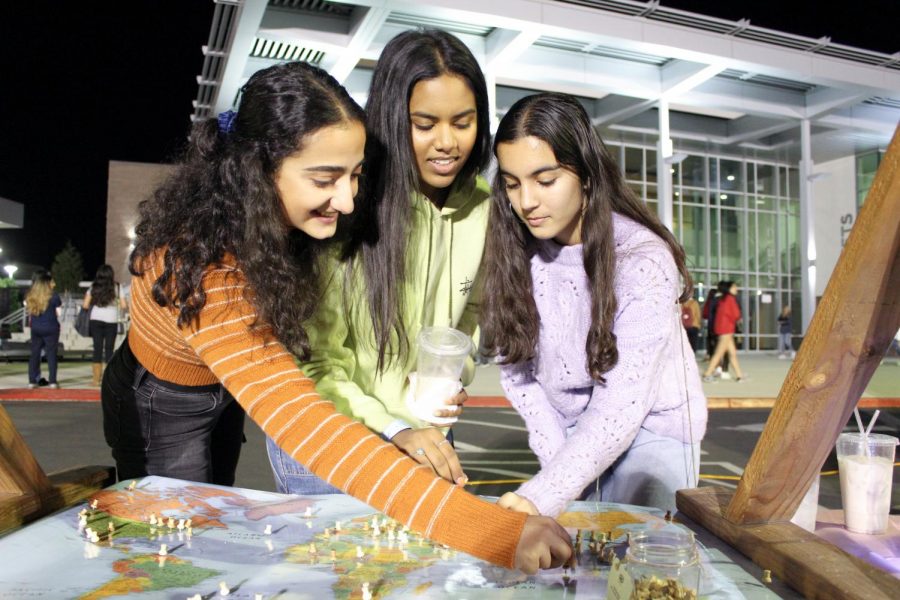 ORIGINS: Seniors Saghar Rafie, Akshita Agirishetti and Nelly Safi plot a point on the map to represent the place they are from.