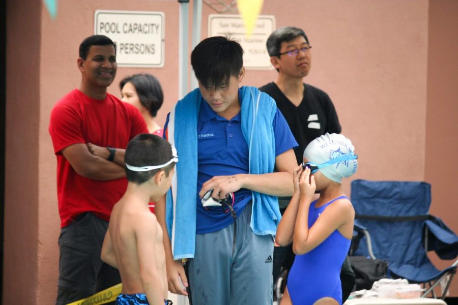 HUDDLE UP: Junior Kendrick Pham shares his expertise with a couple of young swimmers.