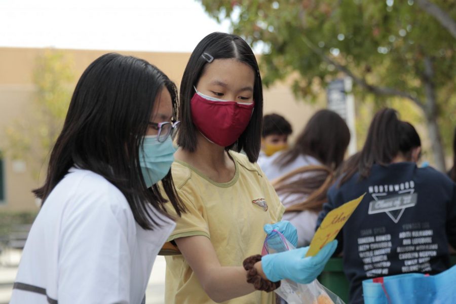 WE CAN DO IT: With masks and gloves to prevent the spread of COVID-19, sophomore class president Rachel How and vice president Eugenie Chang package thank-you cards and food donations.