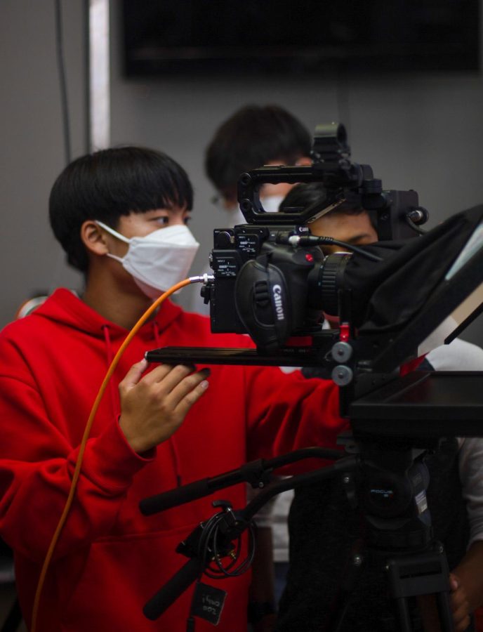 ON AIR: Assistant show producer senior Matthew Son prepares the camera to record the desk hosts for the second episode of NTV.