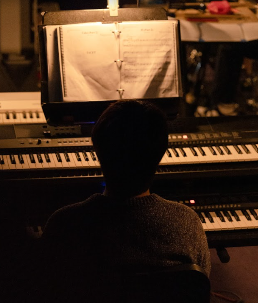 PEEK INTO THE PIT: Junior Howard Wu plays the keyboard under the pit’s dim lighting.