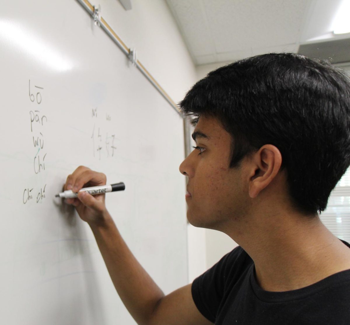 BRIDGING CULTURES: Junior Arjun Patel practices his Mandarin through writing and sound out words.