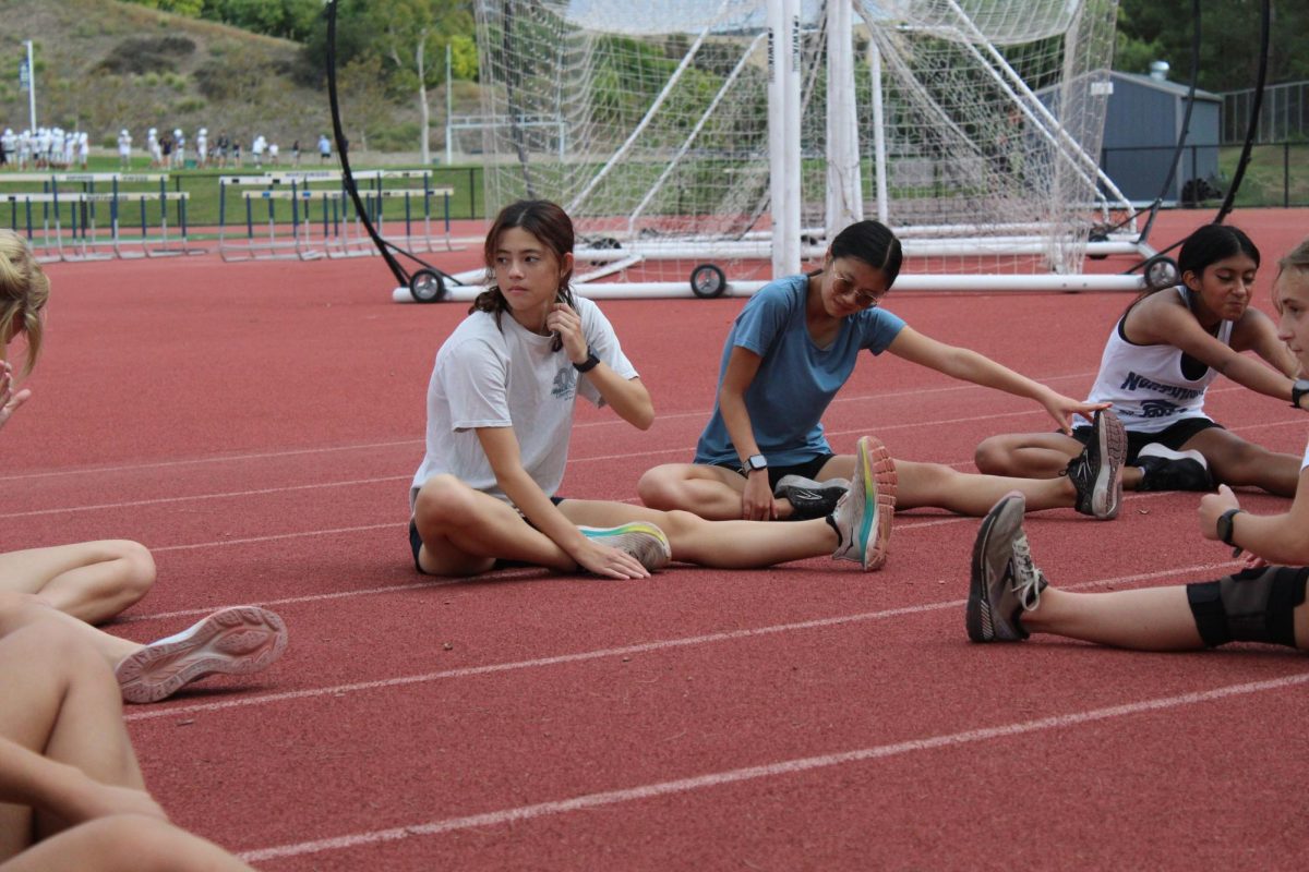TIME FOR TACKLING TRIATHLON TRAINING:  Senior Madison Ledgard (left) stretches before cross country practice.