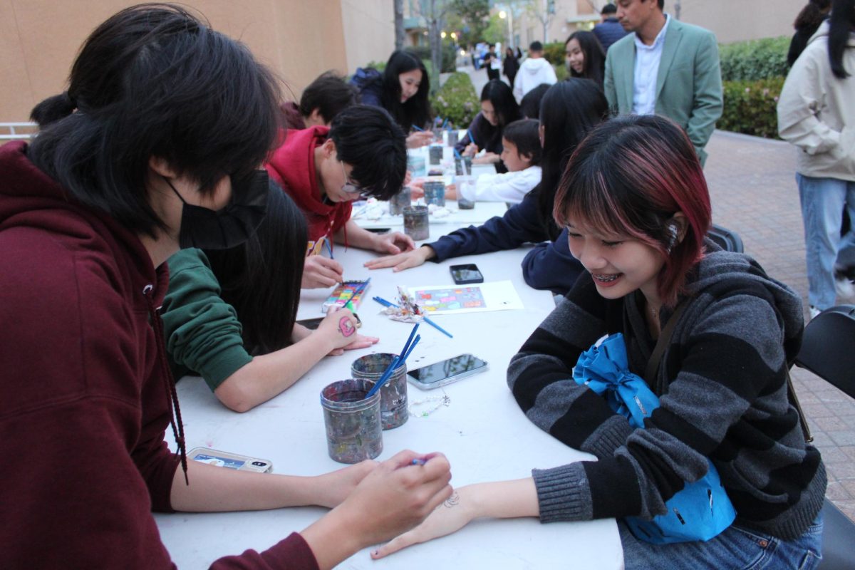 HANDS-ON HUES: Junior Ashley Nguyen gets a spider painted on her hand during Night of the Arts.