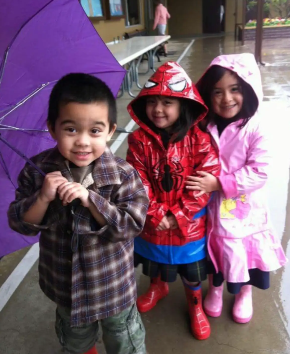 Triplets juniors Noah Wu, Eleanor Wu and Abigail Wu smile together on a rainy day before school in first grade.