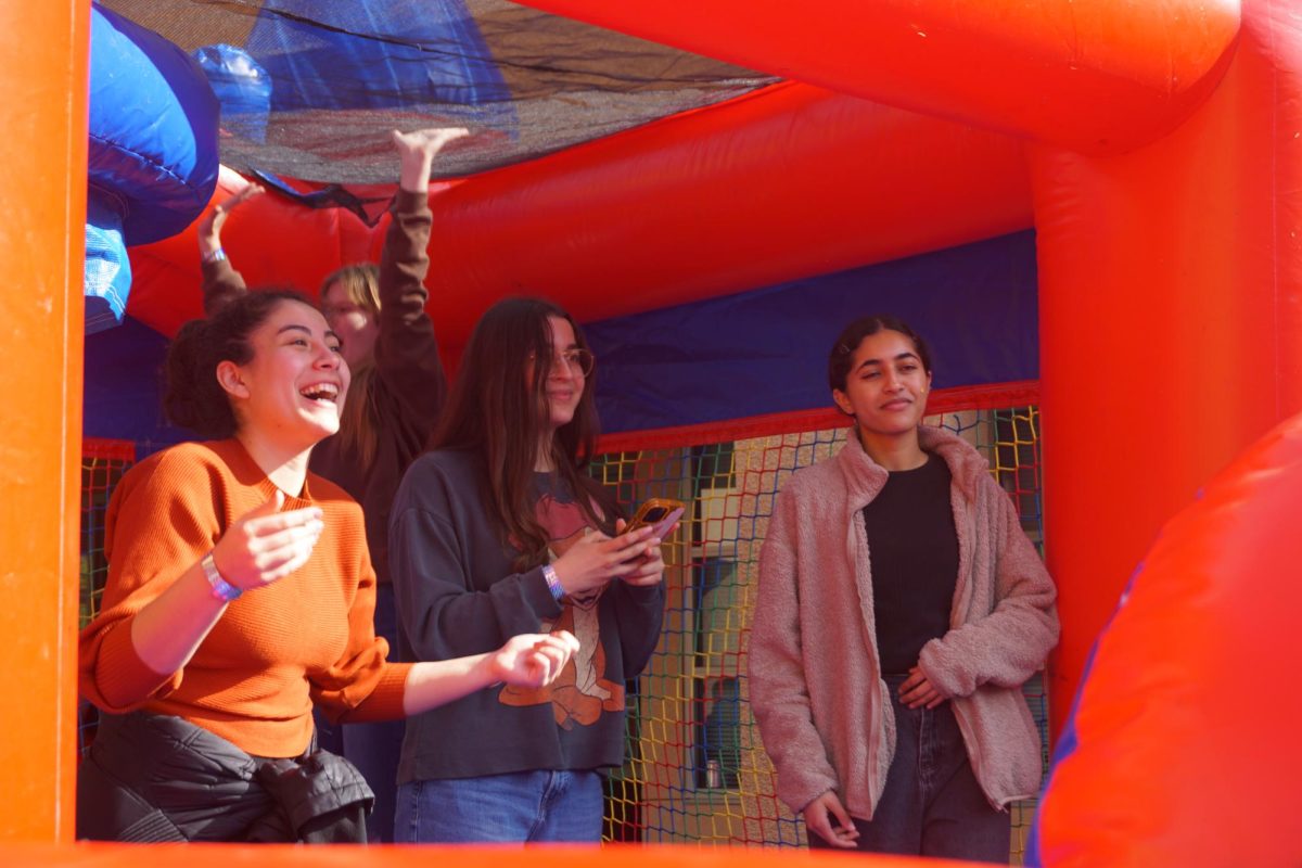SENIOR CELEBRATION: (Left to right) Seniors Izabel Vicente, Esma Hurmali and Lena Hussain laugh together while cheering on their friends completing the bounce house obstacle course at the senior barbecue after school.