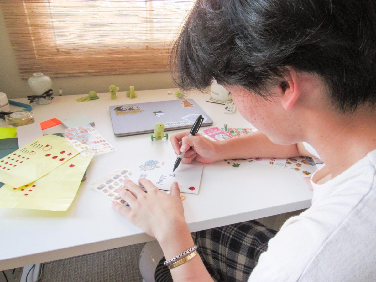 CELEBRATING THROUGH STOCK PAPER, STICKERS AND SHARPIE: Senior William Ryee writes a heartwarming card for a close friend’s birthday. He strategically uses his large sticker collection to decorate and personalize his gift.