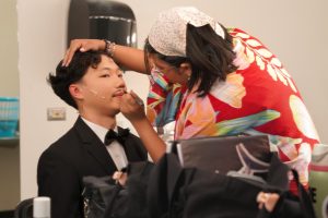 CRAFTING CLUE: Costume head junior Kaylee Fernandez perfects Wadsworth’s mustache for Clue play’s dress rehearsal. 