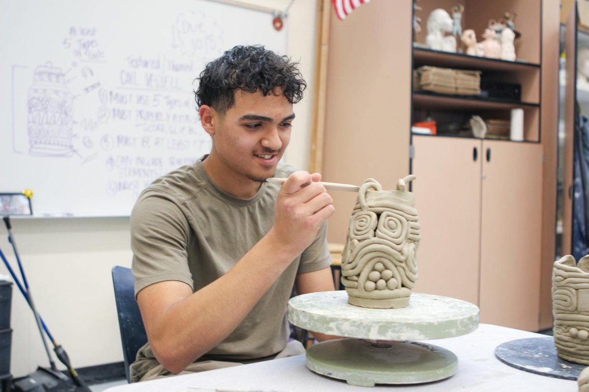 CLAY PLAY: Beginning Ceramics student senior Mohammed Aiyesh perfects the final touches of his coil vessel before heading to the kiln