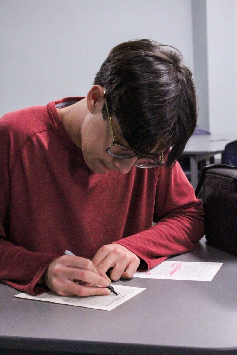 BLACKOUT POETRY: Senior Louis Gaigneux creates poetry by blacking out parts of book pages at Dead Poets Society’s weekly club meeting.