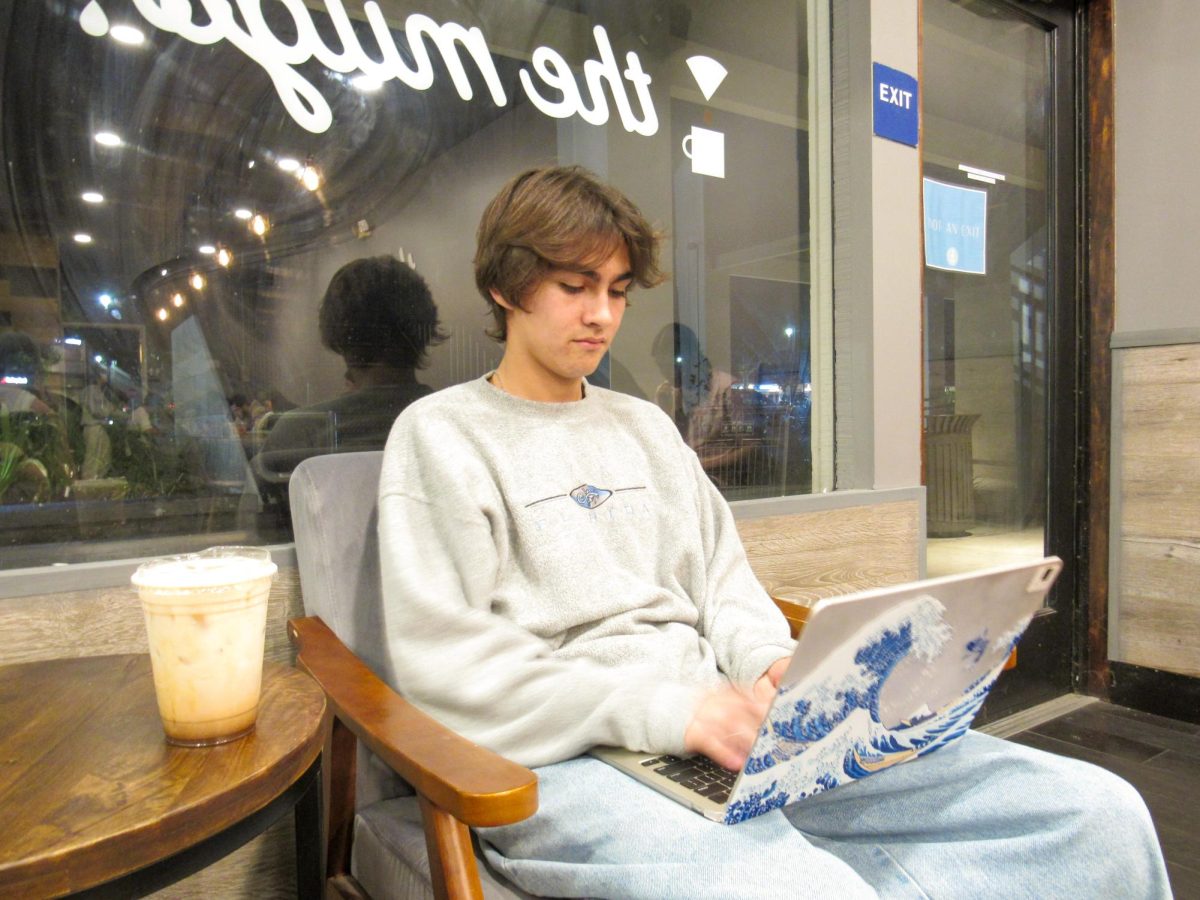  CRAMMING ON CAFFEINE: Senior Santi Vanegas sips on a honey lavender latte, one of the house species from The Mugs menu, while working on his schoolwork. 