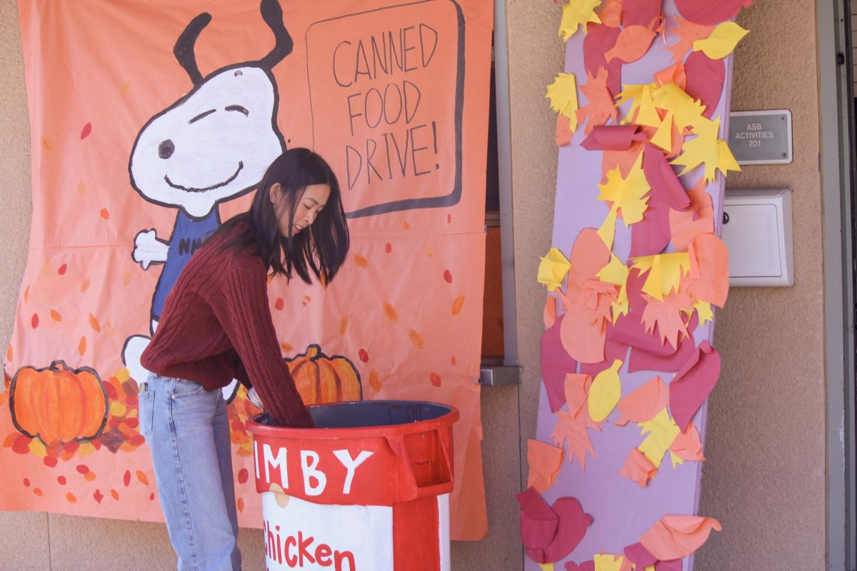 GIVING BACK: Senior Katherine Jiang donates cans to the canned food drive bins outside of the SAC.