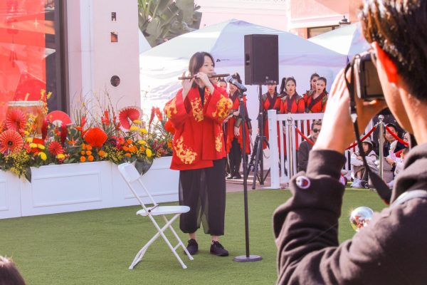  CAPTURING THE FESTIVITY: At the Spectrum Lunar New Year Celebration, sophomore Jiwoo Park snaps photos of a performer playing on a dizi, a type of Chinese flute.