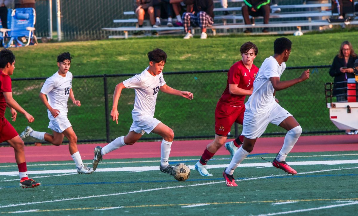 CHARGING TO SUCCESS: Senior Ryan Loo dribbles towards the goal in a varsity boys soccer game.