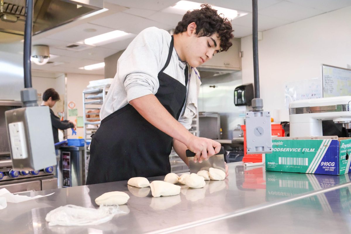 CLASSROOM TO KITCHEN: Sophomore Cameron Sabbaghian slices roti dough for his classmates to enjoy with their chicken curry.