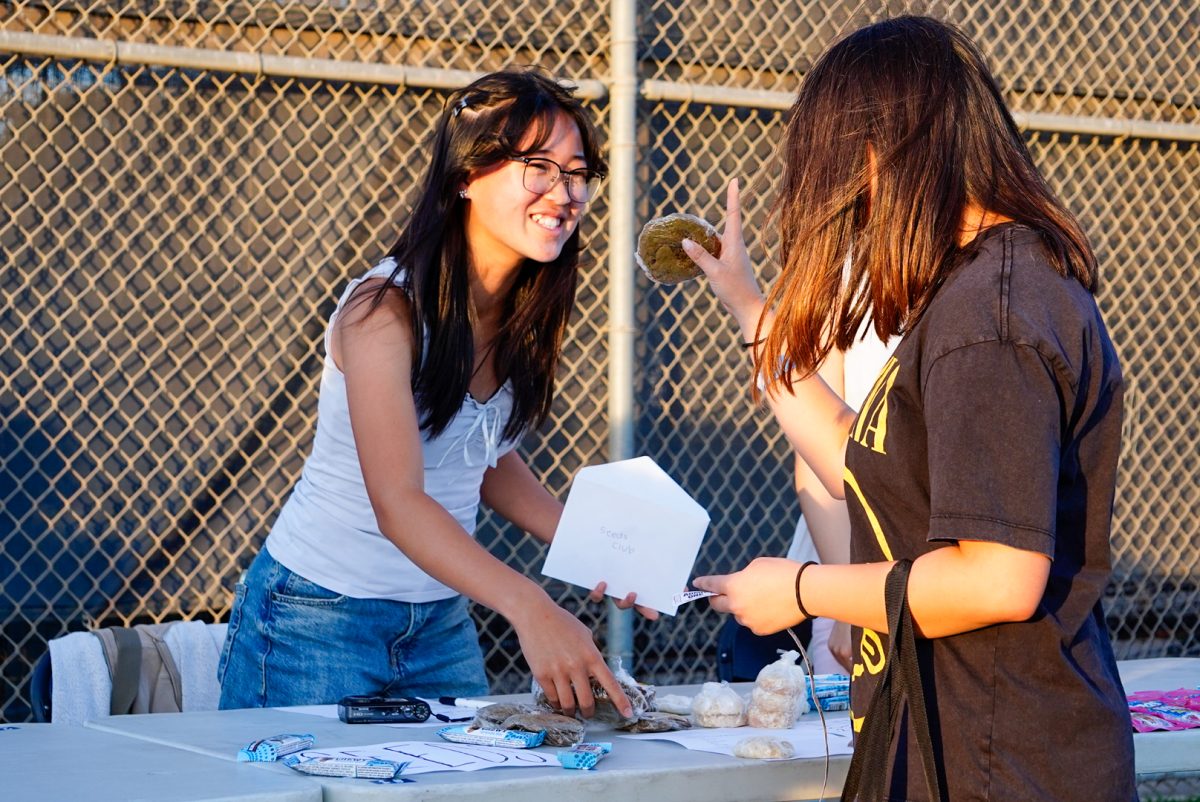Sophomore Ella Yu sells a matcha brownie to a friend as a part of the Seeds Club at Sophomore Movie Night.