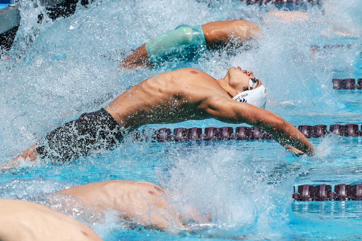MAKING WAVES: Senior Derek Hitchens gets a powerful start during the 100-yard backstroke, securing a second place finish.