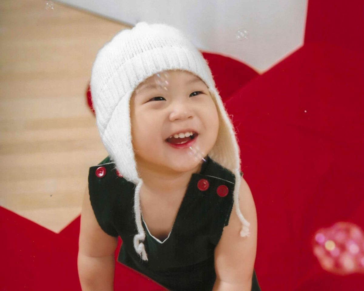 DÉRACINEMENT: A one-year-old’s innocent grin, a fleeting warmth of fragile light before the gathering shadows.