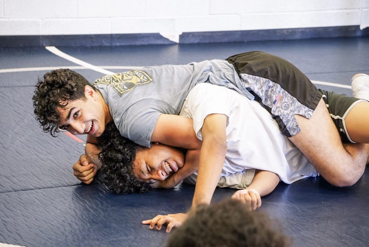 FRIENDLY FIRE: Junior Keon Rezazadeh playfully wrestles Junior Steve Cruz as he pins him to the ground.
