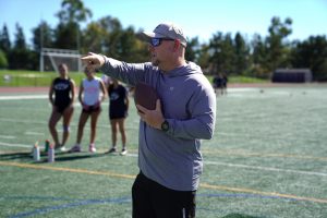 STRATEGY IN MOTION: During drills, assistant girls flag football coach Steven Plette helps break down routes to sharpen the team’s game.