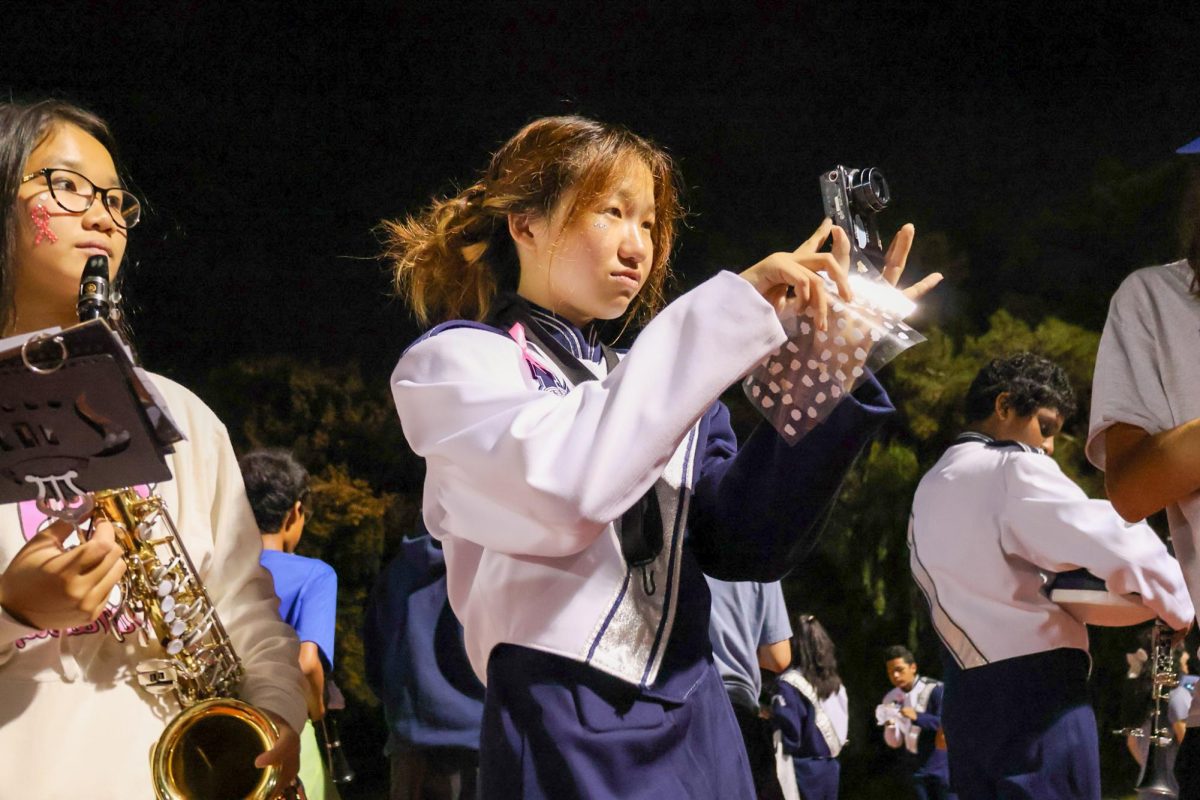 SAY CHEESE: With phone use banned for Northwood performers at football games, Marching Band saxophonist sophomore Ashley Zheng is one of many to take photos for friends using a digicam.