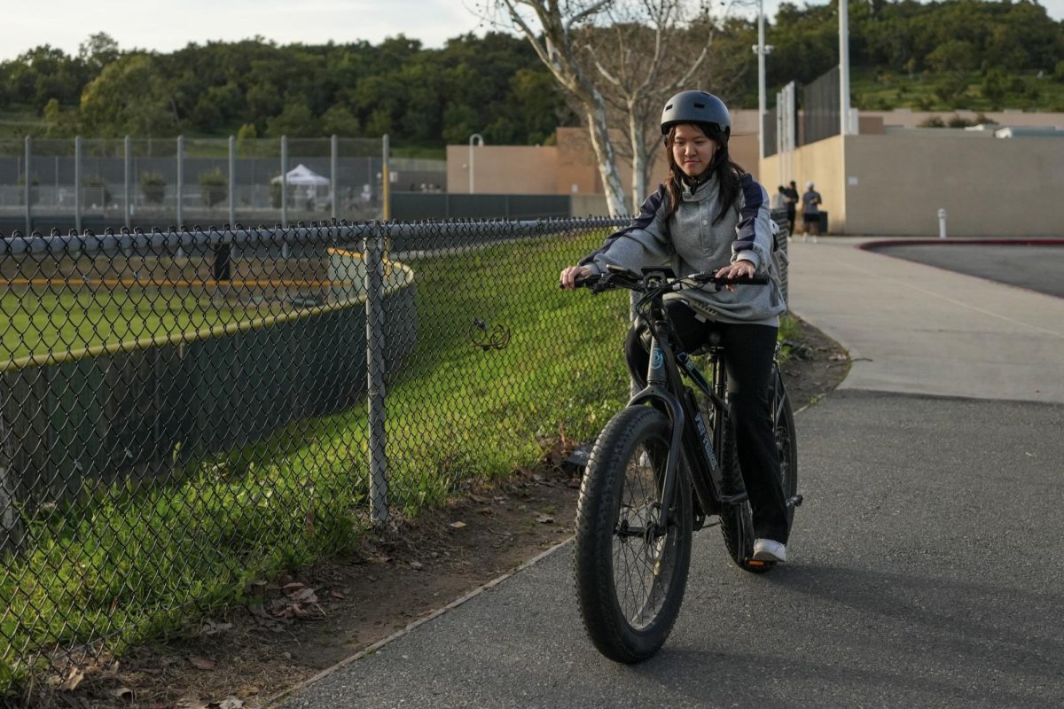 SLOW DOWN, SAFE ZONE: Senior Amy Liang rides her e-bike to school, following the new updated e-bike regulations on school sidewalks.